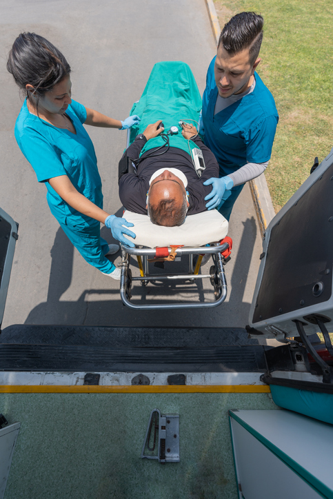 Trabajadores de una ambulancia transportan a un paciente con collarín en una camilla